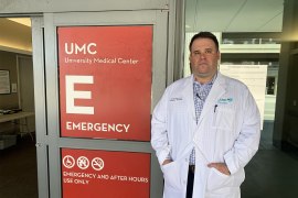 A photo of a man standing in front of a hospital door.